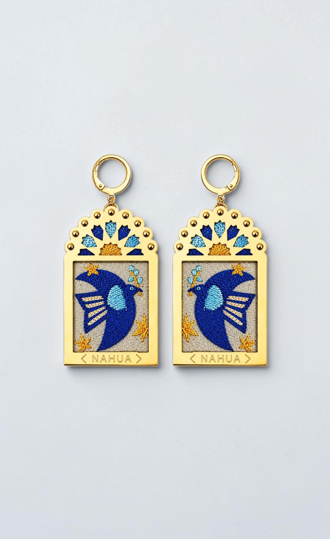 Paire de boucles d'oreilles Dorie de la collection Dwara par Nahua, ex-voto dorés brodés représentant une colombe bleue entourée d'étoiles.