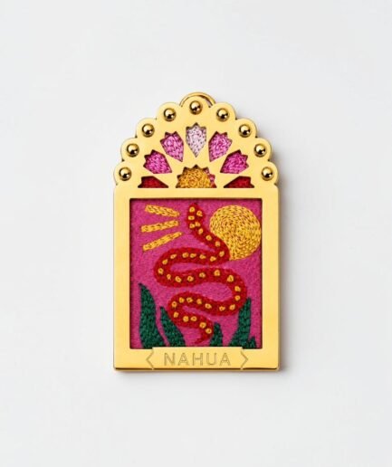 Charm Dwara Nahua en métal doré et broderie représentant un serpent rouge devant un soleil doré sur fond rose.
